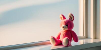 Beautiful bright plush toy sitting on a windowsill on a clear sunny day. photo