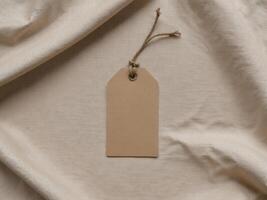 Blank Kraft Paper Tag With Rustic String Loop on Textured Fabric Background. photo
