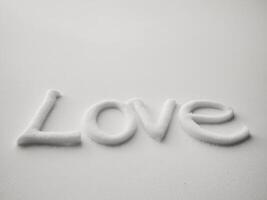 LOVE written in snow with soft shadows on white surface. photo