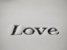 LOVE written in snow with soft shadows on white surface. photo