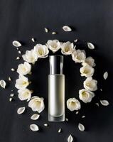 Perfume bottle on dark background surrounded by freesia flowers and petals. photo