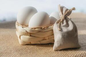 White eggs in a basket on a background of burlap photo