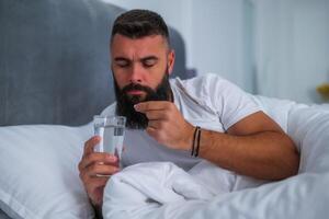 Man can not sleep. He is taking sleeping pill. photo