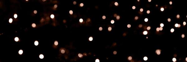 Blurry garland lights on a dark background. Festive Christmas and New Year background. Soft focus. Image toned in color of 2025 year - Mocha Mousse photo
