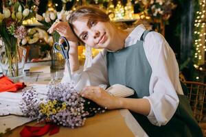 A woman in her florist shop collects bouquets of flowers. The concept of a small business. Bouquets of tulips for the holiday on March 8. photo