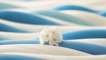 A white flower sits on top of a blue and white wave photo