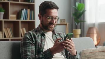 caucasiano homem masculino cara às casa feliz sorridente positivo olhando Móvel telefone usando Smartphone mostrando celular Telefone tela exibição verde chromakey modelo aplicativo local na rede Internet Internet conectados serviço internet video