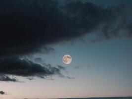 A full moon is seen in the sky above a cloudy sky photo