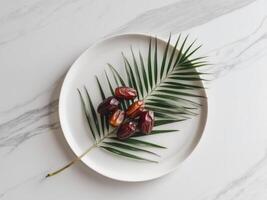 Dates on a plate with palm leaf on marble background photo