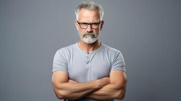 An older man with glasses and a beard standing with his arms crossed photo