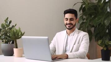 A man in a white shirt is sitting at a desk with a laptop photo