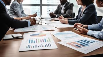Business people sitting at a table with papers and graphs photo
