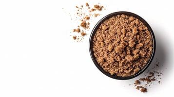 A bowl of brown sugar on a white surface photo
