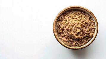 A bowl of brown sugar on a white surface photo