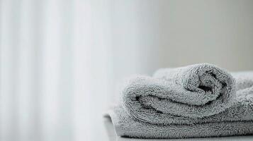 A folded towel on a table in front of a window photo