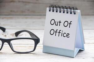 Side view of Out Of Office text on white notepad. Off work concept photo