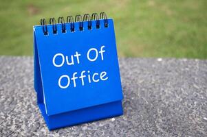 Side view of Out Of Office text on blue notepad. Off work concept photo