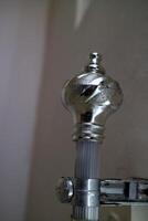 The curtain pole end cap with a round tapered shape with a chrome color, made of plastic photo