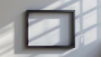 Empty Black Frame Against a Wall with Natural Light Shadows photo