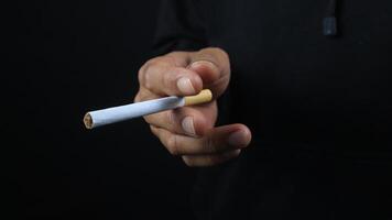 a man's hand holds a cigarette, black background photo