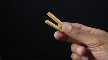 hand holding crispy straw biscuit sticks on black background. photo