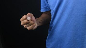 Man showing clenched fist in aggression concept photo, black background photo