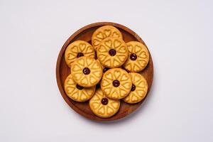 Strawberry jam biscuits on a wooden plate, decorated with a circular heart motif on their surface, isolated on white background. High resolution photo. photo