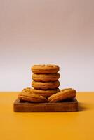 Pile of strawberry jam biscuits on a wooden plate, decorated with a circular heart motif on their surface, isolated on white and orange background. High resolution photo. photo