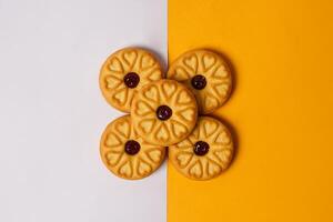Strawberry jam biscuits on white and orange background, decorated with a circular heart motif on their surface. High resolution photo. photo