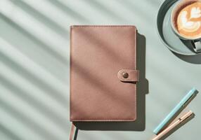 Leather notebook with pens and latte in sunlit setting photo