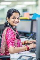 Smiling professional Indian woman in traditional attire working at an office desk photo