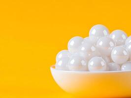 A bowl full of white balls on a yellow background photo
