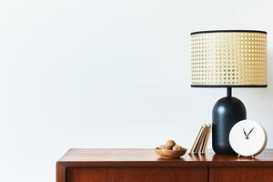 Scandinavian interior with stylish teak commode, design decoration, black rattan lamp, clock, copy space and elegant personal accessories. Modern living room in classic house. Template. photo