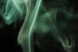 A close up of smoke on a black background, green shapes in the darkness photo