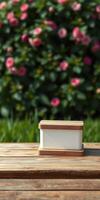 Beautiful outdoor setting with a wooden table holding a white container surrounded by blooming flowers in soft light photo