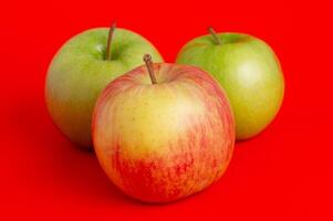 Three red apples and two green ones on a red background. photo