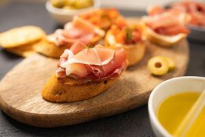 Tasty bruschettas with cheese and Prosciutto di Parma ham served with wine on gray background photo