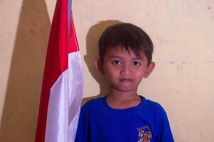 silhouette of a little boy taking a photo with a red and white flag