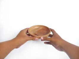 The image shows a pair of hands holding a round wooden bowl with a smooth surface. The plain white background emphasizes the natural texture and grain patterns of the wood, photo