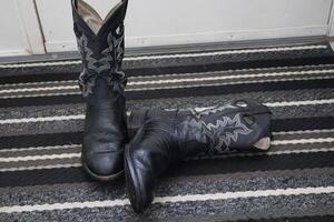Pair of western boots, kicked of at the door. One flat on the floor. photo