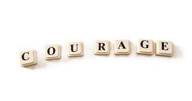 Courage, spelled out in white block letters with black ink. photo