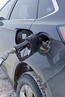 A fuel pump nozzle inserted into the fuel tank of a vehicle. photo