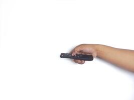 a hand holding a black remote control against a plain white background. The focus is on the remote, highlighting its buttons and ergonomic design. photo
