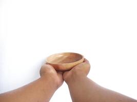 The image shows a pair of hands holding a round wooden bowl with a smooth surface. The plain white background emphasizes the natural texture and grain patterns of the wood, photo