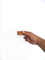 The image shows a hand holding a little round wooden bowl with a smooth surface. The plain white background emphasizes the natural texture and grain patterns of the wood, photo