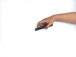 a hand holding a black remote control against a plain white background. The focus is on the remote, highlighting its buttons and ergonomic design. photo