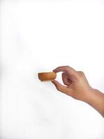 The image shows a hand holding a little round wooden bowl with a smooth surface. The plain white background emphasizes the natural texture and grain patterns of the wood, photo