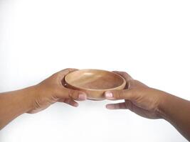 The image shows a pair of hands holding a round wooden bowl with a smooth surface. The plain white background emphasizes the natural texture and grain patterns of the wood, photo
