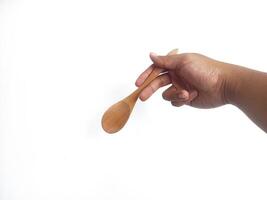 The image shows a hand holding a round wooden spoon with a smooth surface. The plain white background emphasizes the natural texture and grain patterns of the wood, making the bowl the central focus. photo