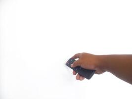 a hand holding a black remote control against a plain white background. The focus is on the remote, highlighting its buttons and ergonomic design. photo
